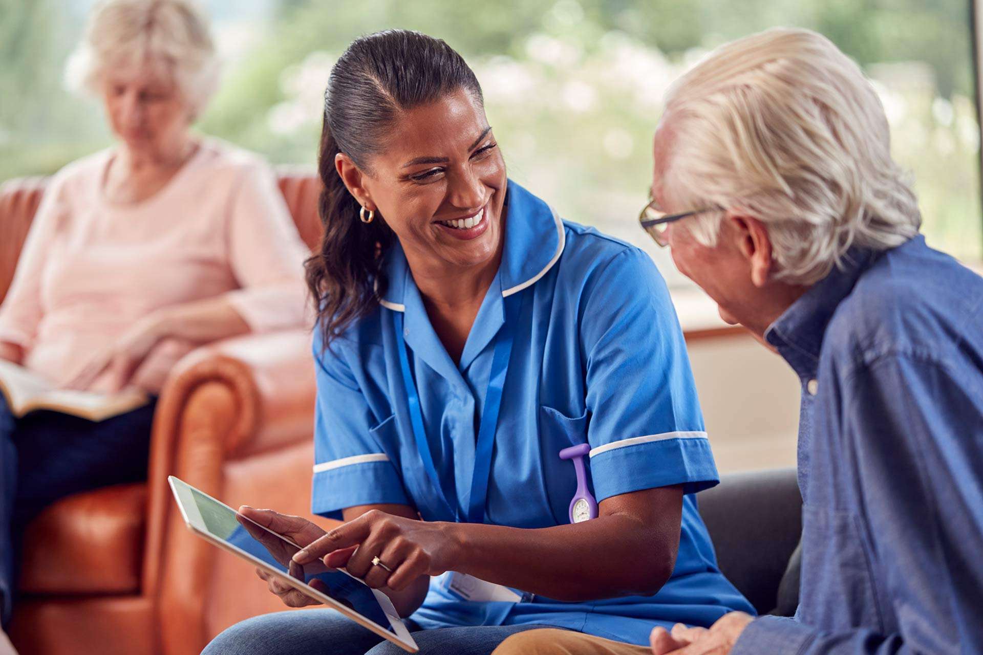 senior couple at home with man talking to female nurse